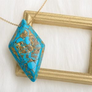 Le collier Ellen a une forme de losange avec des arêtes biseautées et présente un recto avec une magnifique imitation de la pierre de turquoise symbole d'équilibre de positivité et de sérénité un véritable art bijou